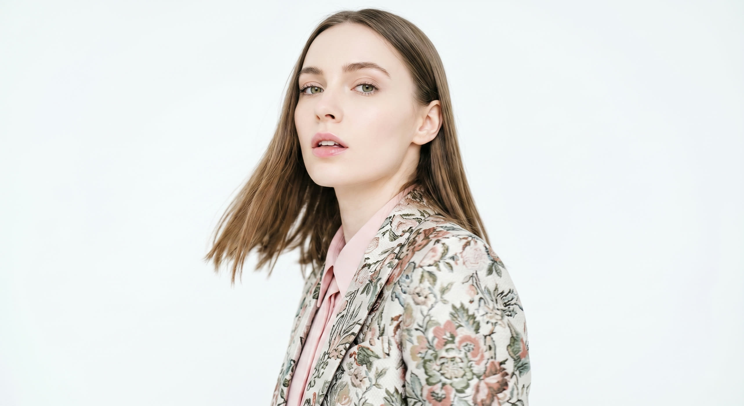 Ritratto in movimento della modella con blazer in jacquard floreale su fondo chiaro